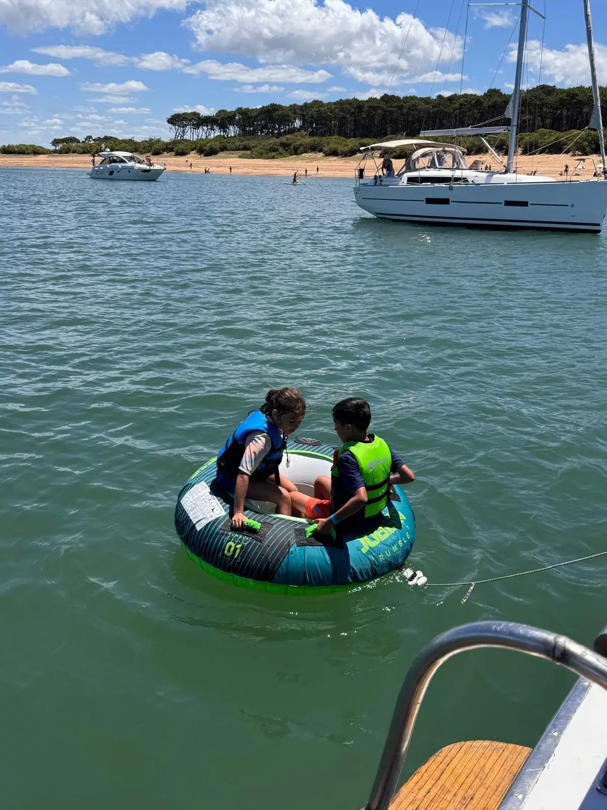Niños en un inflable junto al barco, fondeado frente a la playa y los pinos de Isla Gorriti